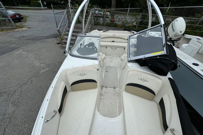 Slide: The Image of 2016 Stingray 198 RX boat interior with seating and steering wheel, parked on pavement. - 9