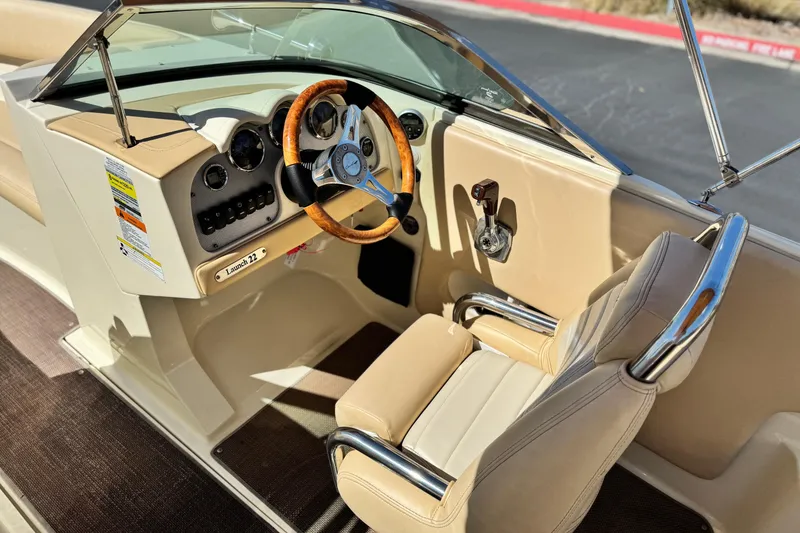 Slide: The Image of 2013 Chris-Craft Launch 22 boat interior with beige seating and wooden steering wheel. - 24