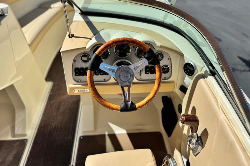 Slide: The Image of 2013 Chris-Craft Launch 22 boat interior with wooden steering wheel and dashboard controls. - 25