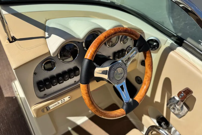 Slide: The Image of 2013 Chris-Craft Launch 22 dashboard with wooden steering wheel and control panel. - 26