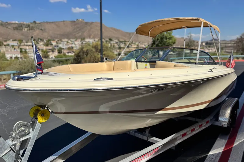 Slide: The Image of 2013 Chris-Craft Launch 22 boat on trailer, beige exterior, bimini top, scenic background. - 3