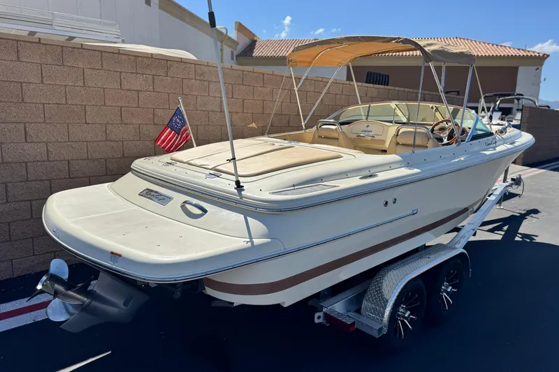 Slide: The Image of 2013 Chris-Craft Launch 22 boat on trailer, beige interior, American flag, sunny day. - 5