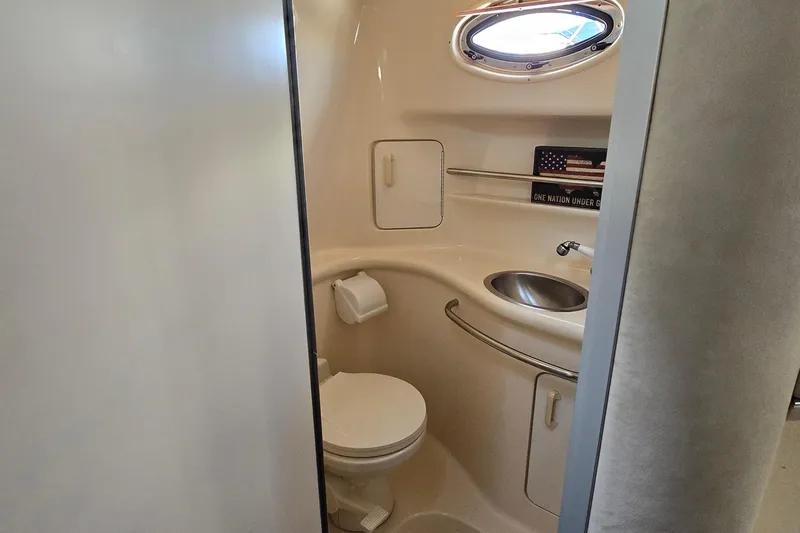 Slide: The Image of 1995 Sea Ray 330 Sundancer bathroom with toilet, sink, and porthole window. - 31
