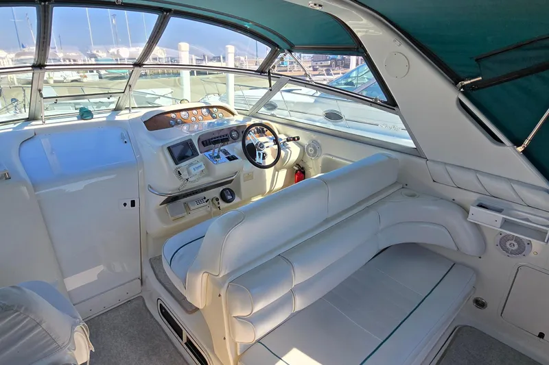 Slide: The Image of 1995 Sea Ray 330 Sundancer cockpit with white seating and helm, docked at marina. - 5