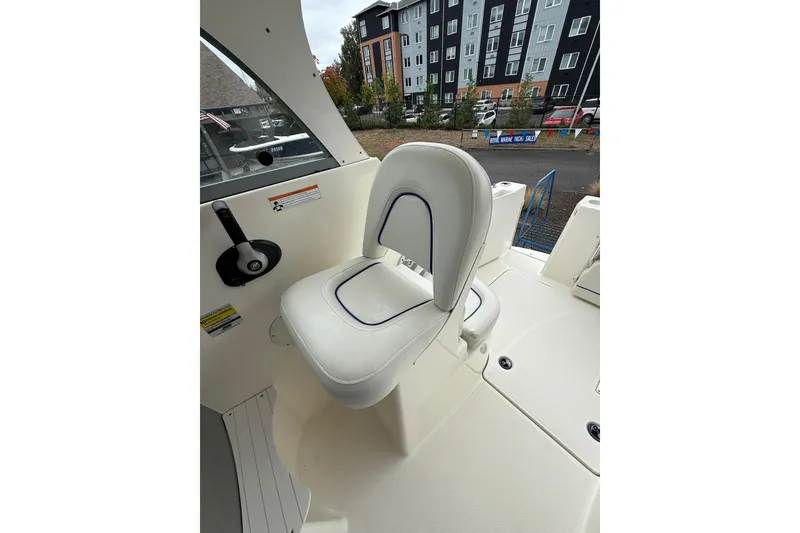 Slide: The Image of 2007 Bayliner 246 Discovery boat interior with white captain's chair and control panel. - 10