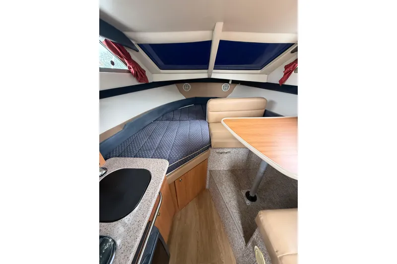 Slide: The Image of 2007 Bayliner 246 Discovery cabin interior with seating, table, and bed. - 16