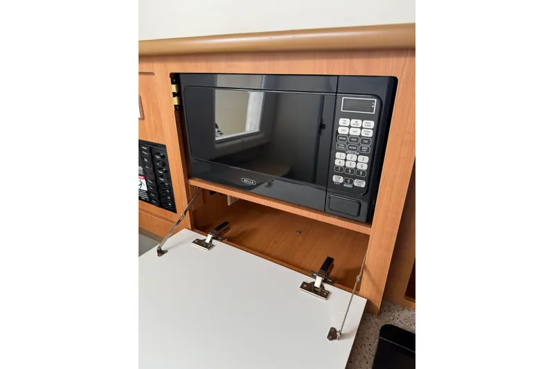 Slide: The Image of 2007 Bayliner 246 Discovery interior with built-in microwave and wooden cabinetry. - 21