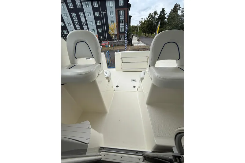 Slide: The Image of 2007 Bayliner 246 Discovery boat interior with seating, docked near modern buildings. - 24