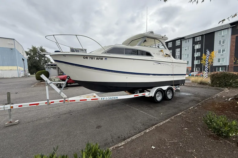 Slide: The Image of 2007 Bayliner 246 Discovery boat on trailer in parking lot, overcast sky. - 4