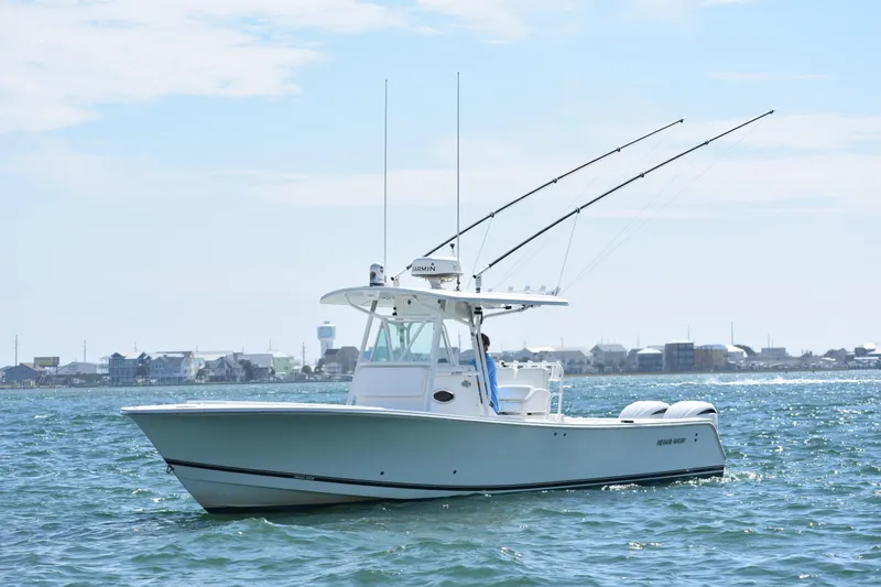 Slide: The Image of 2008 Regulator 32 Forward Seating boat on water with fishing rods, coastal background. - 1