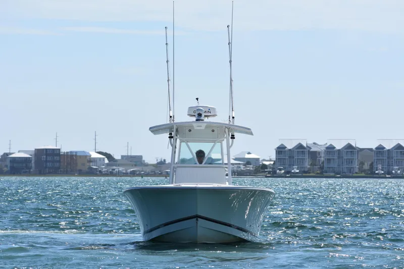 Slide: The Image of 2008 Regulator 32 Forward Seating boat cruising on a sunny day near coastal buildings. - 2