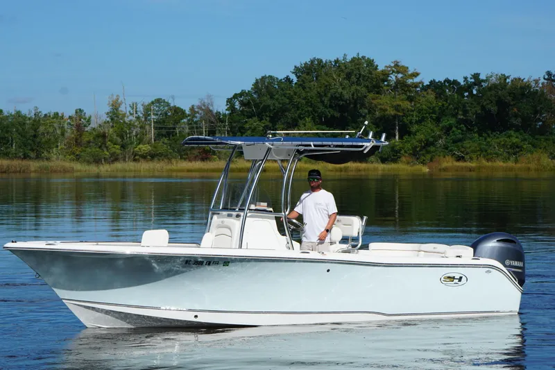 The Image of 2020 Seahunt 234 Ultra boat on calm water with a person at the helm. - 1