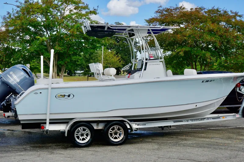 Slide: The Image of 2020 Seahunt 234 Ultra boat on trailer, parked outdoors with trees in background. - 2