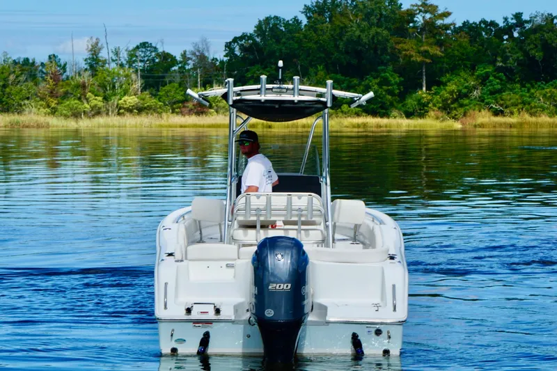 Slide: The Image of 2020 Seahunt 234 Ultra boat cruising on a calm lake with lush green shoreline. - 3