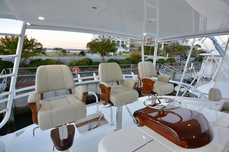 Slide: The Image of 2019 Viking 68 Convertible yacht helm with luxurious seating and polished wood accents. - 50