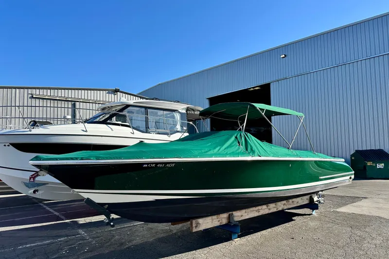 Slide: The Image of 2002 Chris-Craft Launch 28 boat with green cover, parked outside a warehouse. - 7