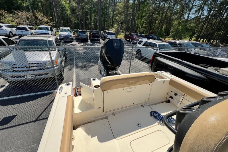 Slide: The Image of 2021 Scout 235 XSF boat interior with motor, parked near cars and trees. - 5