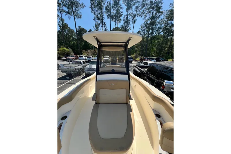 Slide: The Image of 2021 Scout 235 XSF boat with seating, parked outdoors in a wooded area. - 6