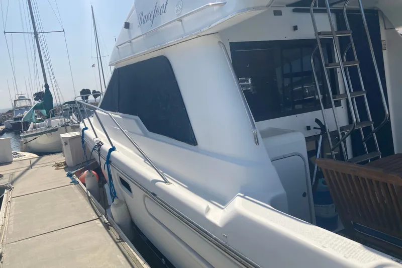 Slide: The Image of 1999 Bayliner 3388 Command Bridge Motoryacht docked at marina, side view with ladder. - 2