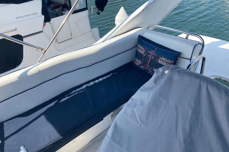 Slide: The Image of 1999 Bayliner 3388 Command Bridge Motoryacht with cushioned seating and nautical-themed pillow. - 29