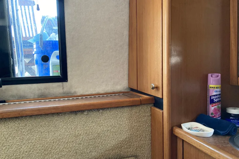 Slide: The Image of Interior of 1999 Bayliner 3388 Command Bridge Motoryacht with wooden cabinets and cleaning supplies. - 46