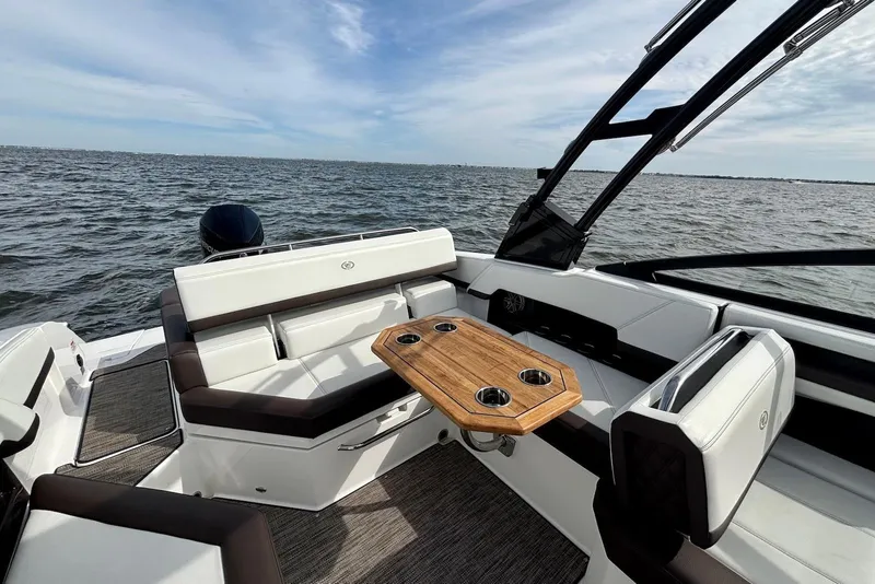 Slide: The Image of 2024 Cobalt R4 Outboard boat interior with seating and wooden table on open water. - 12