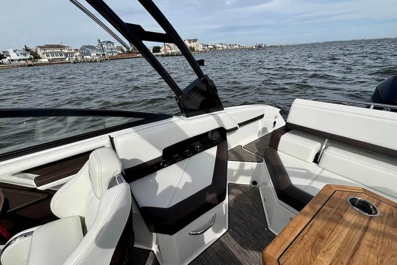 Slide: The Image of 2024 Cobalt R4 Outboard interior with white seating, wooden table, and waterfront view. - 13