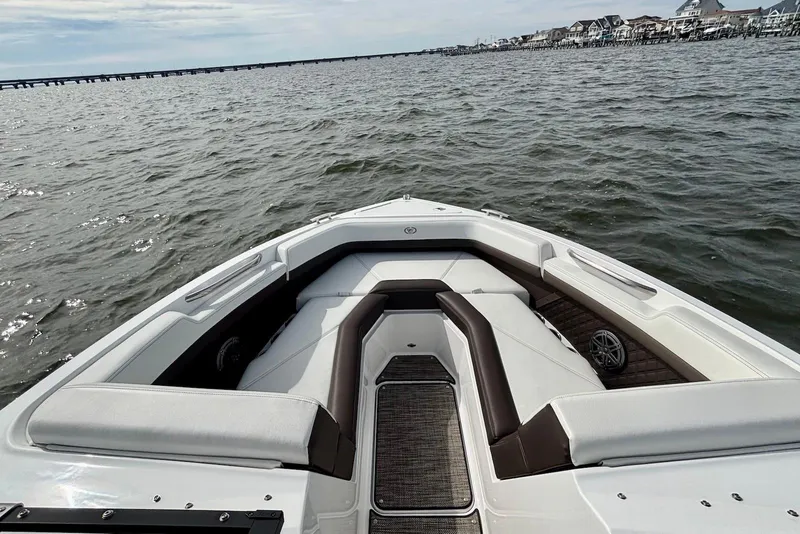 Slide: The Image of 2024 Cobalt R4 Outboard boat interior with cushioned seating, on a calm water body. - 15