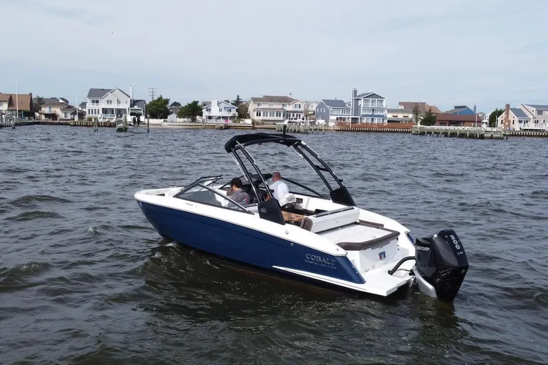 Slide: The Image of 2024 Cobalt R4 Outboard boat cruising on a coastal waterway near residential homes. - 3