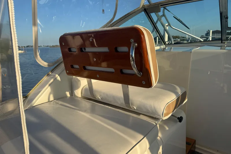 Slide: The Image of 1997 Wellcraft 3300 Coastal boat interior with cushioned seating and wooden backrest. - 11