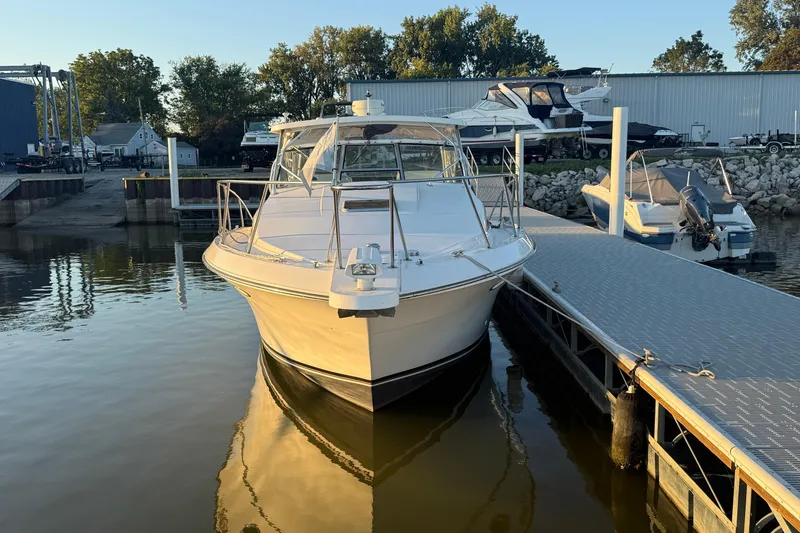 Slide: The Image of 1997 Wellcraft 3300 Coastal boat docked at marina, surrounded by calm water and other vessels. - 3