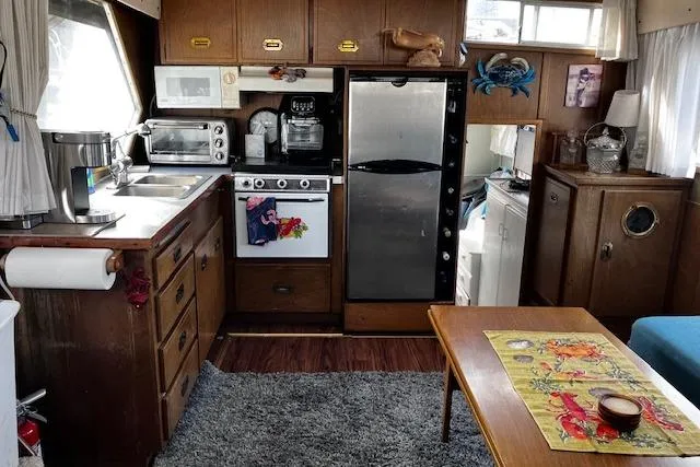 Slide: The Image of 1973 Tollycraft 40' Aft Cabin kitchen with appliances, wooden cabinets, and cozy decor. - 10