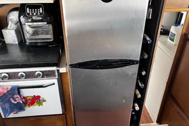 Slide: The Image of 1973 Tollycraft 40' Aft Cabin kitchen with stainless steel fridge and stove. - 16