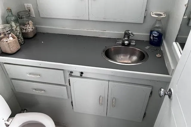 Slide: The Image of 1973 Tollycraft 40' Aft Cabin bathroom with sink, countertop, and storage cabinets. - 19