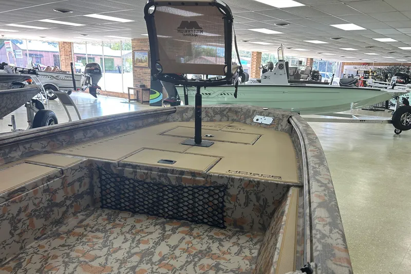 Slide: The Image of 2026 Xpress HD16DB boat with camouflage interior in showroom setting. - 2