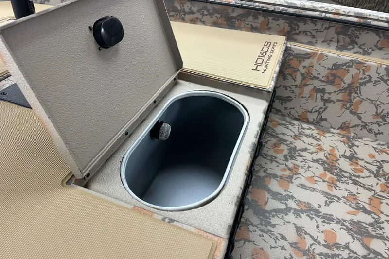 Slide: The Image of Open storage compartment in 2026 Xpress HD16DB hunting boat with camo interior. - 4