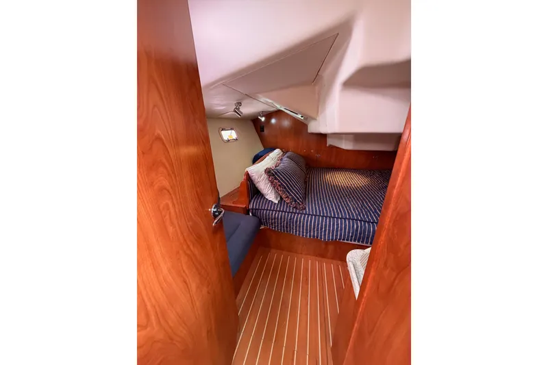 Slide: The Image of Cozy cabin interior of 2009 Hunter 38 sailboat with striped bedding and wooden finishes. - 46