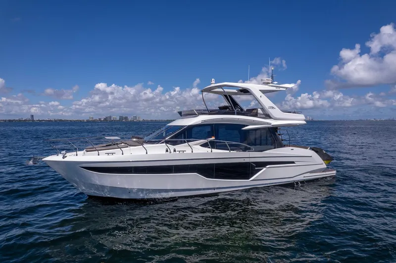 Slide: The Image of 2021 Galeon 500 Fly yacht cruising on open water under a clear blue sky. - 21
