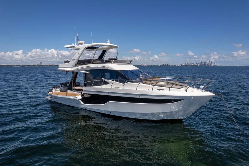 Slide: The Image of 2021 Galeon 500 Fly yacht on open water with city skyline in background. - 9