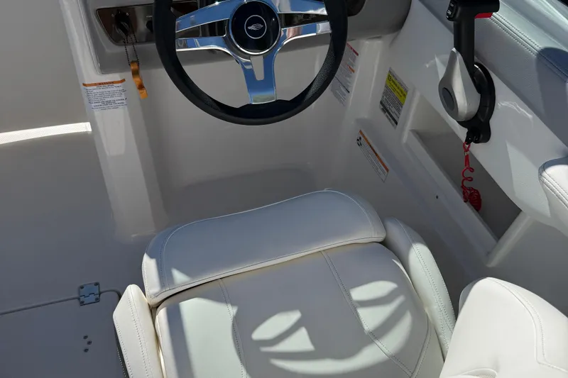 Slide: The Image of 2024 Chaparral 23 SSi OB boat cockpit with steering wheel and white seating. - 10