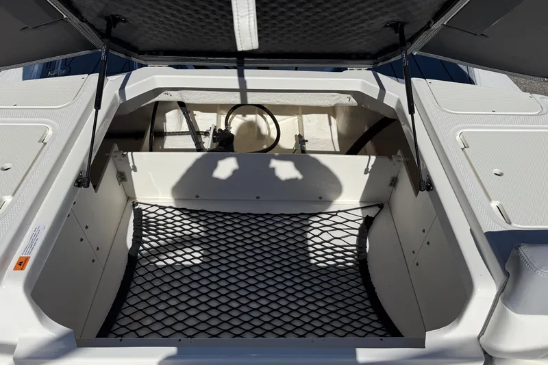 Slide: The Image of 2024 Chaparral 23 SSi OB boat storage compartment with open hatch and netting. - 16