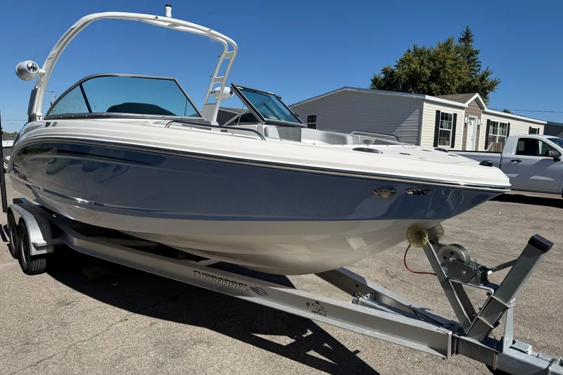 Slide: The Image of 2024 Chaparral 23 SSi OB boat on trailer, parked outdoors under clear blue sky. - 24