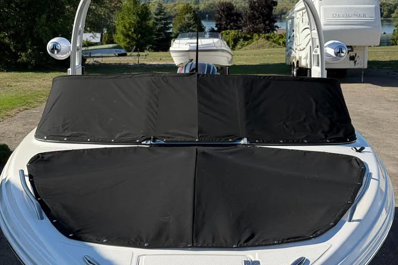 Slide: The Image of 2024 Chaparral 23 SSi OB boat with black cover, parked outdoors. - 3