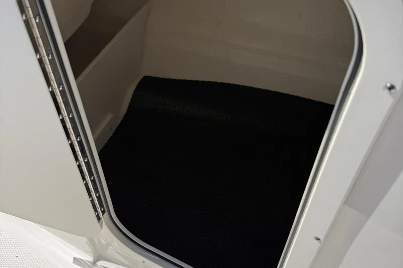 Slide: The Image of 2024 Chaparral 23 SSi OB boat interior storage compartment with black flooring. - 6