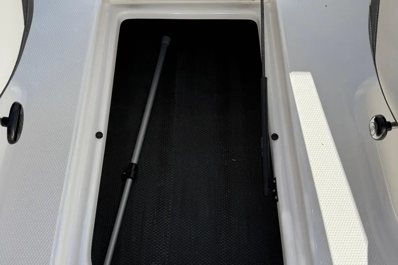 Slide: The Image of 2024 Chaparral 23 SSi OB boat storage compartment with black interior and white trim. - 8