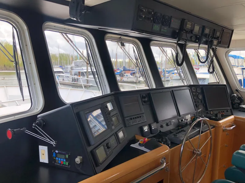 Slide: The Image of 2003 Cape Horn Trawler helm with navigation equipment and steering wheel, docked at marina. - 14