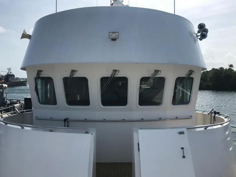 Slide: The Image of 2003 Cape Horn Trawler with white exterior and multiple windows, docked near water. - 49
