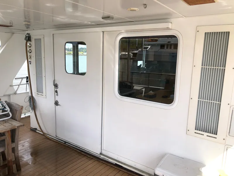 Slide: The Image of 2003 Cape Horn Trawler deck with white door and window, wooden flooring, and outdoor seating. - 52