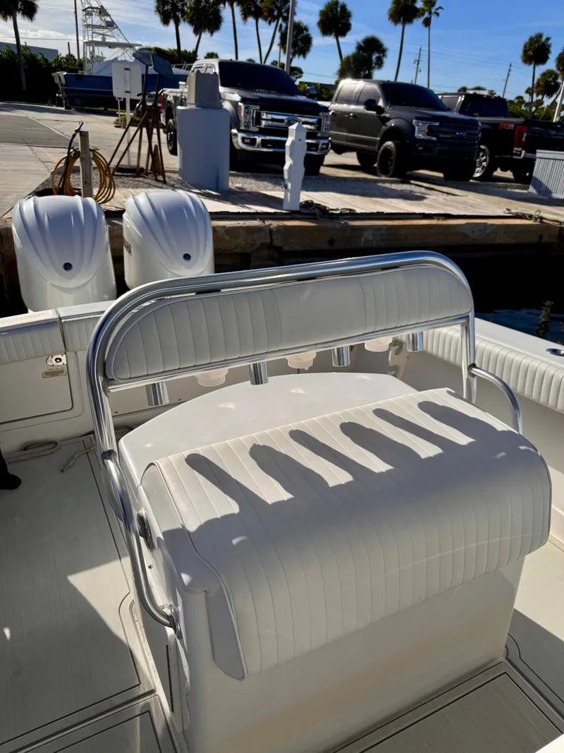 Slide: The Image of 2008 Jupiter 30 boat interior with white seating, docked near trucks and palm trees. - 26