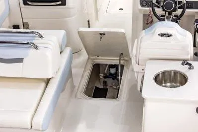 Slide: The Image of 2026 Robalo R257 Dual Console interior with seating, storage hatch, and sink. - 7